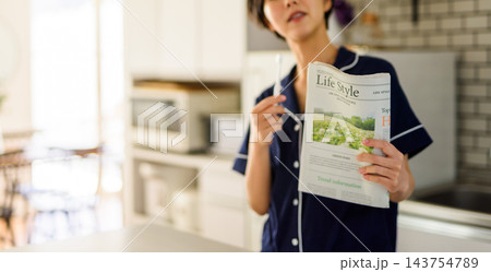 朝食時に新聞を読む若い女性 朝食時に新聞を読む若い女性 143754789