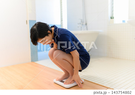 体重計に乗って数値を確認する女性 体重計に乗って数値を確認する女性 143754802