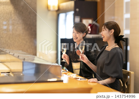 和食店のカウンター席でシャンパンを楽しむ2人の女性 143754996