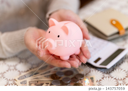 ピンクの豚の貯金箱を持つミドル・シニア女性 143757059