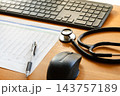 木目のデスクに置かれた聴診器とパソコンと検査データの書類 143757189