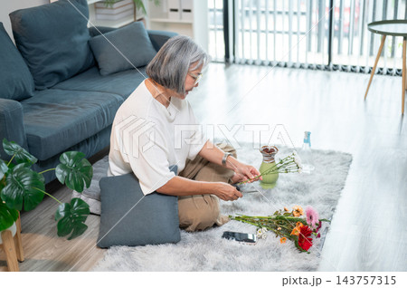 Senior Asian Woman Trimming Flower Stem Arranging Vase in Living Room 143757315