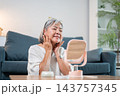 Happy senior woman admiring glowing skin in mirror. 143757345