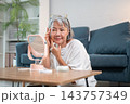 Senior asian woman checking wrinkles on her temple in mirror. 143757349