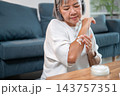 Senior asian woman applying moisturizing body lotion on her arm. 143757351