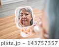 Reflection in mirror of a senior asian woman checking her facial skin. 143757357
