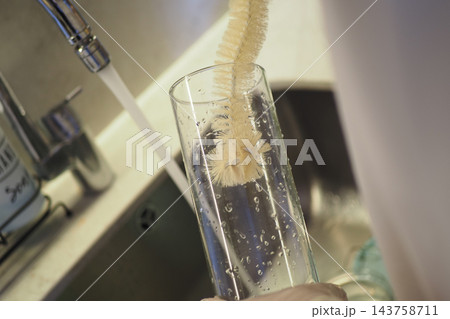 Cleaning Glass With Bottle Brush in Kitchen Sink Under Running Water for Sparkling Glassware Cleaning Glass With Bottle Brush in Kitchen Sink Under Running Water for Sparkling Glassware 143758711