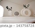 Digital thermometer and plant decor arranged on an indoor shelf 143758728