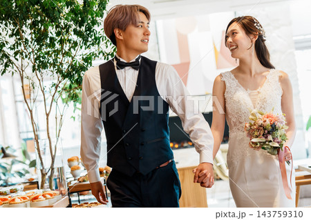 結婚式の披露宴で手を繋いで入場する新郎新婦 143759310