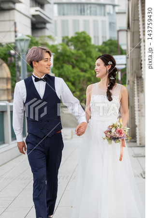 都会の橋の上を手をつないで歩く新郎新婦 143759430