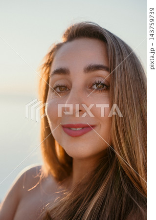 Woman portrait smiling female close up enjoying sunset at the beach during golden hour for summer lifestyle concept 143759739