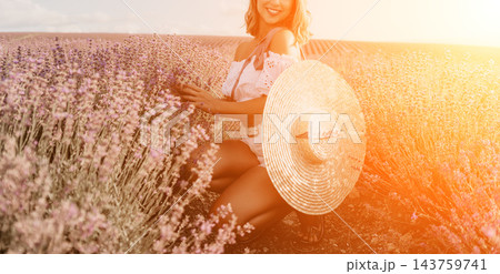Lavender woman summer Smiling young woman squatting in a purple flower field during sunset holding a large straw hat Lavender woman summer Smiling young woman squatting in a purple flower field during sunset holding a large straw hat 143759741