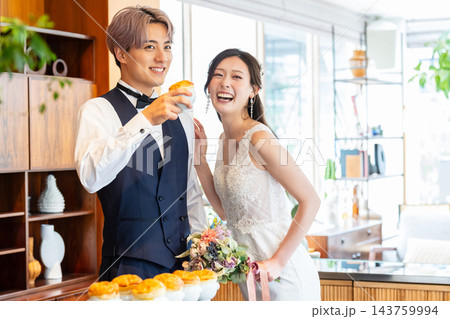 ウェディングパーティーで料理を前に微笑む新郎新婦 ウェディングパーティーで料理を前に微笑む新郎新婦 143759994