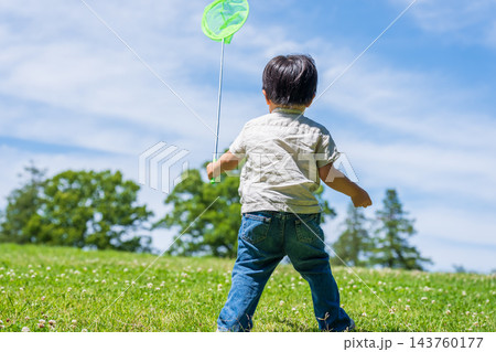 虫取り網を持って草原を駆ける男の子の後ろ姿 143760177