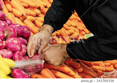 Market vendor hand arranging fresh carrots and red turnips at stall Market vendor hand arranging fresh carrots and red turnips at stall 143760336