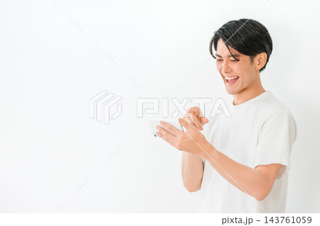 スマホで面白い投稿を見て大笑いする20代の若い男性。 スマホで面白い投稿を見て大笑いする20代の若い男性。 143761059