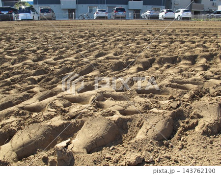 元農地に新築された賃貸住宅と農耕車の轍の残る秋の畑風景 143762190