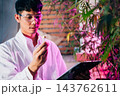 Marijuana researcher Asian man wearing glasses and holding a vial bottle and a clipboard to check list in cannabis sativa hemp plants in cannabis farms 143762611