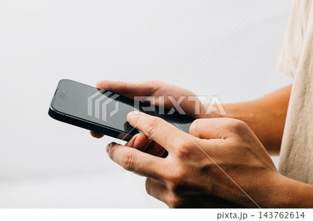 A hand holding a black cell phone isolated on white background, Man hand holding black smartphone mockup blank screen display A hand holding a black cell phone isolated on white background, Man hand holding black smartphone mockup blank screen display 143762614