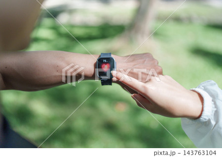 Outdoor exercise partners check a fitness watch Outdoor exercise partners check a fitness watch 143763104