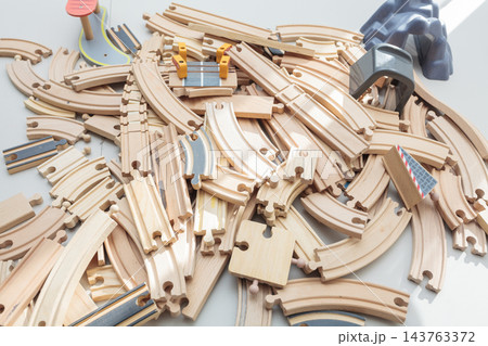 Wooden toy train tracks and railway construction pieces scattered on white background 143763372