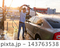 Man rinsing soapy rear window of silver sedan with pressure washer 143763538