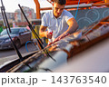 Smiling man wiping wet windshield of car with brown microfiber cloth 143763540