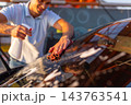 Smiling man wiping wet windshield of car with brown microfiber cloth 143763541