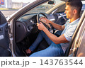 Man polishing dark steering wheel of car with brown microfiber cloth 143763544