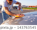 Man spraying cleaning liquid on car roof with trigger bottle 143763545