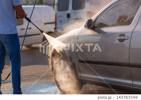 Crop view of a man washing his car by high pressure water gun 143763549
