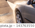 High pressure water stream spraying onto side door of gray car 143763550