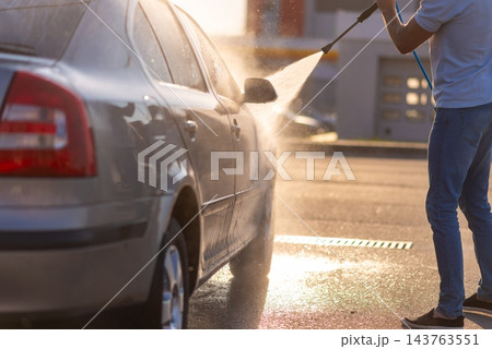 Man washing his car by high pressure water gun 143763551
