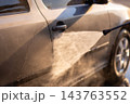 High pressure water stream spraying onto side door of gray car 143763552