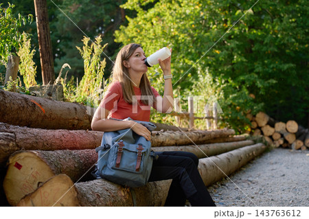 Woman drinking water during hiking break in forest 143763612