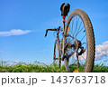 Low angle view of a gravel bike standing on grass under a bright blue sky. 143763718