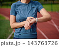 Woman checking smartwatch on running track at stadium 143763726