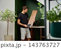 Man holding a wooden shelf and checking the metal bracket before installation 143763727
