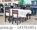 Simple outdoor cafe with heavy wooden tables and chairs 143763851