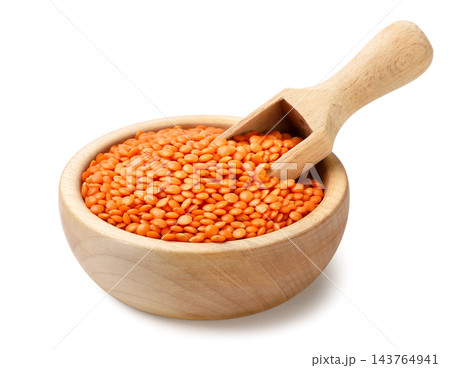 Red lentils in a wooden bowl with a spatula on a white background. Isolated 143764941
