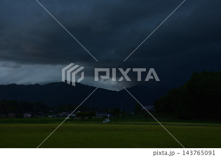 暗雲に覆われた山々と田園風景 143765091