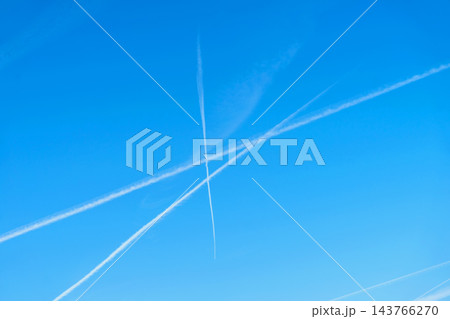 Airplane Contrails Crossing in Clear Blue Sky. Multiple white airplane contrails forming an X shape against vibrant clear blue sky. Natural background, copy space Airplane Contrails Crossing in Clear Blue Sky. Multiple white airplane contrails forming an X shape against vibrant clear blue sky. Natural background, copy space 143766270