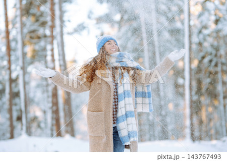 Young woman in warm clothes plays with snow on a sunny winter day. Concept of walking, fun. Young woman in warm clothes plays with snow on a sunny winter day. Concept of walking, fun. 143767493