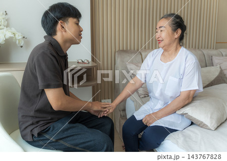 Senior woman receiving care from young man at home for wellness support 143767828