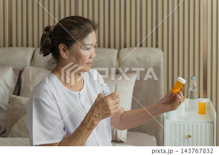 Senior woman managing medication at home for healthy aging lifestyle. 143767832