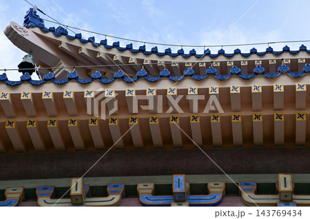 Close-up of the ornate decor on the Chinese classic roof of traditional building, Chinese architecture in China. Chinese folk religion landmark. Buddhist Temple or traditional building. Close-up of the ornate decor on the Chinese classic roof of traditional building, Chinese architecture in China. Chinese folk religion landmark. Buddhist Temple or traditional building. 143769434