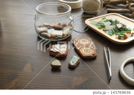 Antique ceramic shards near glass jar on dark wood table. Flatlay beach pottery fragments with tweezers craft materials. Sustainable zero waste mosaic art DIY coastal home decor project. Antique ceramic shards near glass jar on dark wood table. Flatlay beach pottery fragments with tweezers craft materials. Sustainable zero waste mosaic art DIY coastal home decor project. 143769636
