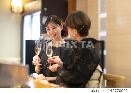和食店のカウンター席でシャンパンを楽しむ2人の女性 143770093