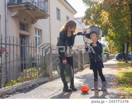 Mother and daughter enjoying Halloween trick or treat in neighborhood 143771376