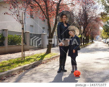 Mother and daughter enjoying Halloween trick or treat in neighborhood 143771377